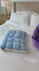 Quilted puff pillow in blue, hands showing the loft